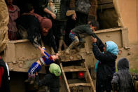 Displaced Iraqi women who fled their homes during a battle between Iraqi forces and Islamic State militants, try to get out of a vehicle with their children at a checkpoint, to be transfer to Hammam al-Alil camp, in Mosul. REUTERS/Thaier Al-Sudani