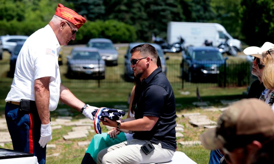 Ryan Schnettler receives a folded American flag after prayers for him and his military war dog Colt during a memorial service at the Michigan War Dog Memorial in South Lyon on June 17, 2023. Schnettler and Colt served together in Afghanistan and he was laid to rest at the cemetery after the ceremony and memorial.