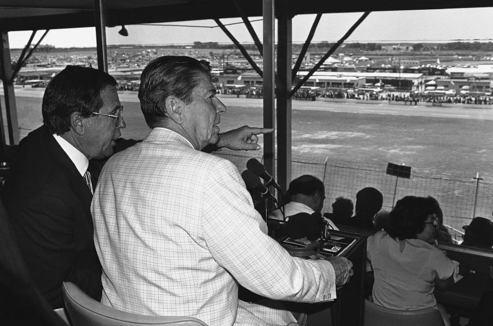 FILE - President Ronald Reagan, front right, sits with William France Jr., president of NASCAR and part owner of the Daytona Speedway, and watches the running of the Firecracker 400 stock car race July 4, 1984, in Daytona Beach, Fla. NASCAR marks its 75th year in 2023, recalling both its highs and lows. (AP Photo/Ira Schwarz, File)