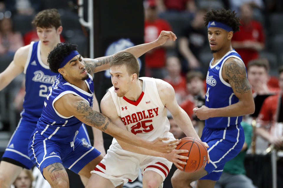 Bradley's Nate Kennell (25) keeps the ball away from Drake's Roman Penn, left, as Drake's Anthony Murphy, right, watches during the second half of an NCAA college basketball game in the semifinal round of the Missouri Valley Conference men's tournament Saturday, March 7, 2020, in St. Louis. (AP Photo/Jeff Roberson)