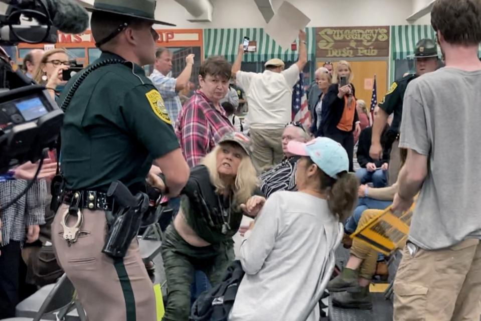 FILE - In this Thursday, Oct. 13, 2021 file photo, New Hampshire State Police remove an audience member, who interrupted proceedings, during a meeting of New Hampshire's Executive Council in Concord, N.H. Republicans in New Hampshire are struggling to contain a wing of their party that is promoting conspiracy views around the Covid-19 vaccine and pushing back, sometimes aggressively, regarding federal mandates to get the shot. (AP Photo/Holly Ramer, File)