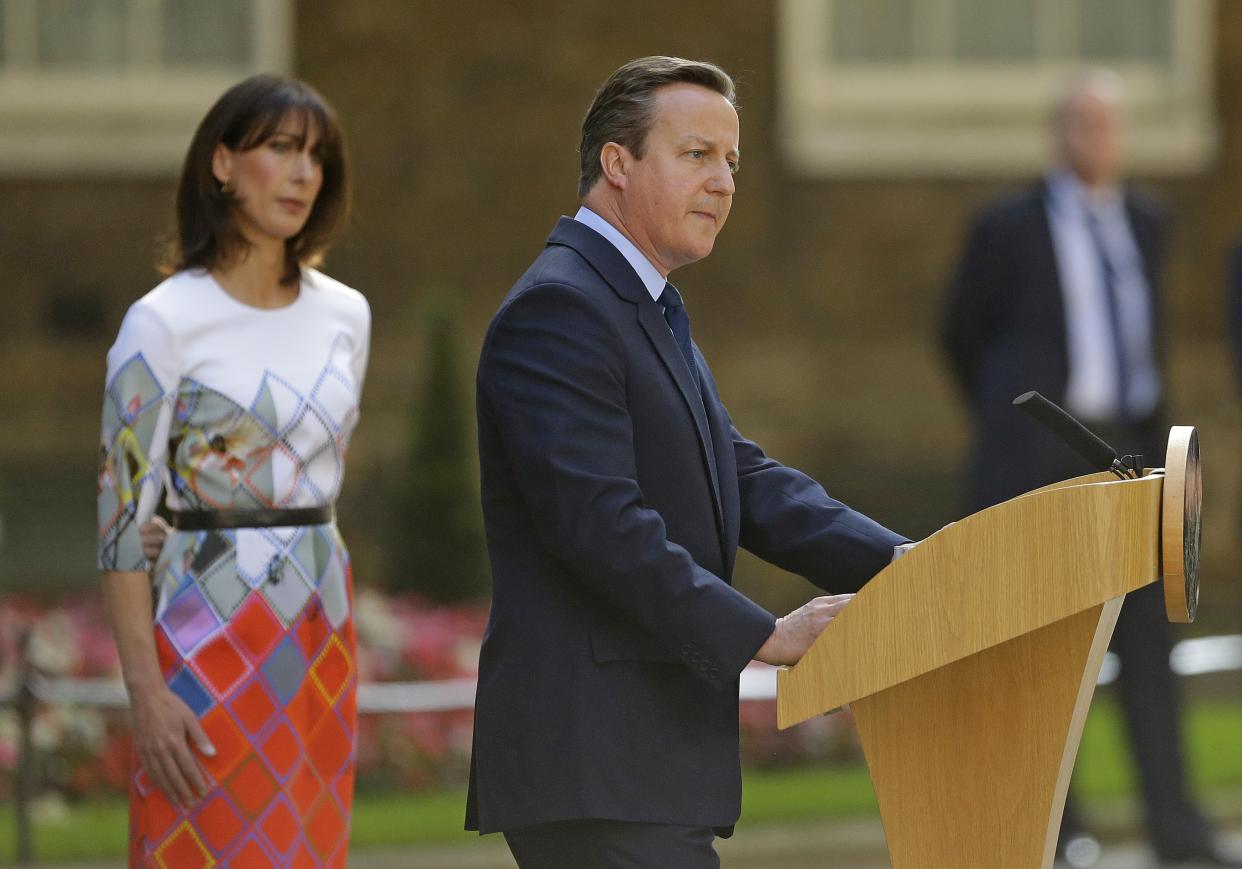 Britain's Prime Minister David Cameron speaks outside 10 Downing Street, London as his wife Samantha looks on Friday, June 24, 2016. Cameron says he will resign by the time of the party conference in the fall after  Britain voted to leave the European Union after a bitterly divisive referendum campaign, according to tallies of official results Friday. (AP Photo/Matt Dunham)