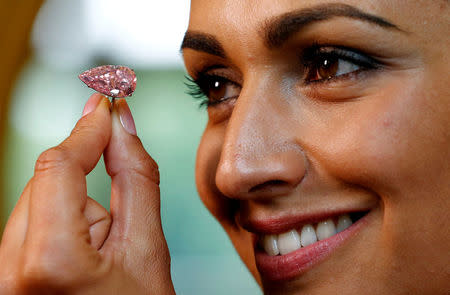 A model poses with the "Unique Pink", a 15.38 carats vivid pink diamond, at Sotheby's auction house in Geneva, Switzerland May 9, 2016. REUTERS/Denis Balibouse/File Photo