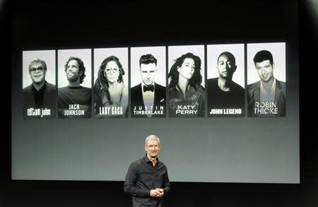 Apple Inc CEO Tim Cook talks about the iTunes Festival with some of the artists expected in the background during Apple Inc's media event in Cupertino