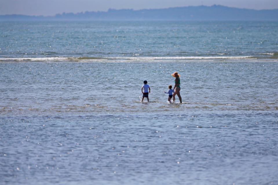 A woman and two young children take advantage of the low tide to walk far out on the sandbar at the Demarest Lloyd State Park in Dartmouth.