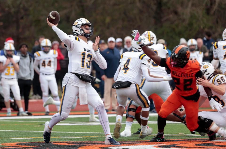 Saline quarterback CJ Carr throws downfield as Belleville's Ray-Mond Smith (22) moves in to try and stop him during first-half action in the MHSAA Division 1 playoff game between Saline and Belleville at Belleville High School on Saturday, Nov. 4, 2023.