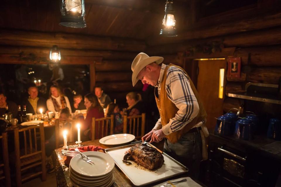 Guests are served an amazing dinner in the cabin after taking the sleigh ride up the mountain. | Courtesy of Lone Mountain Ranch
