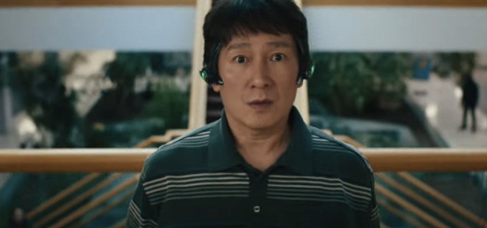 Quan in a a striped shirt with surprised expression in a mall-like setting