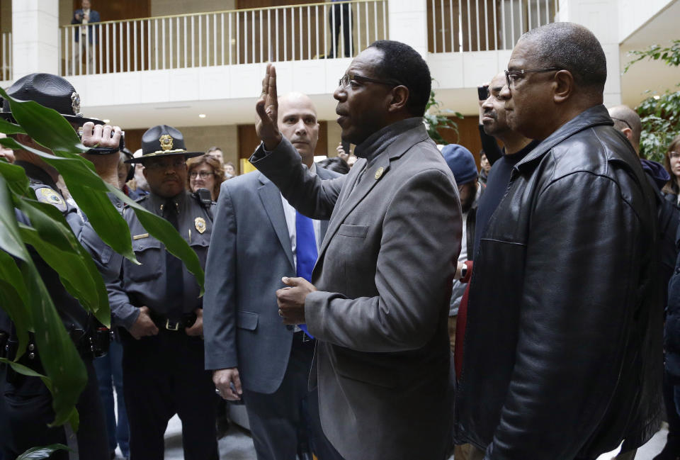 FILE- In this Dec. 15, 2019 file photo, Rev. Curtis Gatewood, with the North Carolina chapter of the NAACP raises a hand as he is confronted by General Assembly police at a demonstration during a special session of the North Carolina Legislature in Raleigh, N.C. In a written statement to The Associated Press Tuesday, Oct. 1, 2019, Rev. Gatewood said he never intentionally harassed anyone. He realized his actions "may have been received as sexual." (AP Photo/Gerry Broome, File)