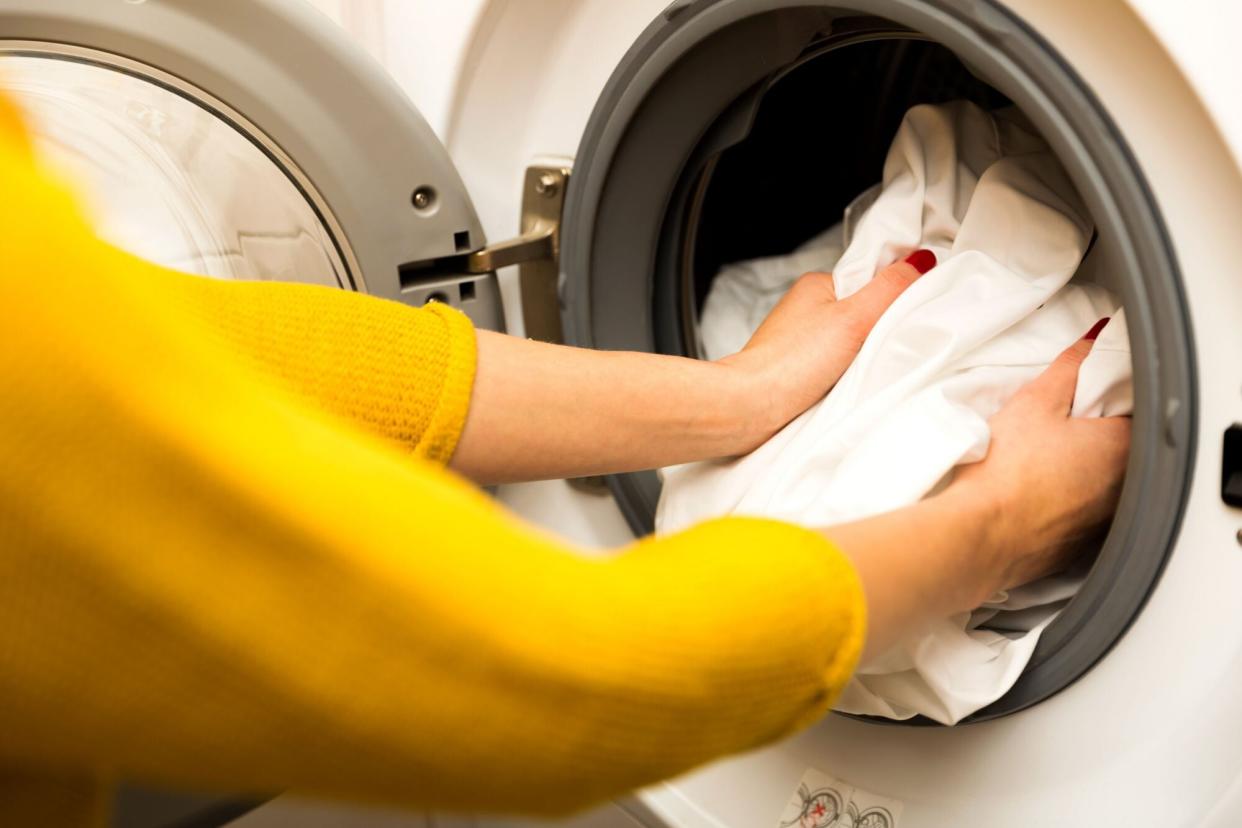 Woman Puttiing Laundry in Washing Machine