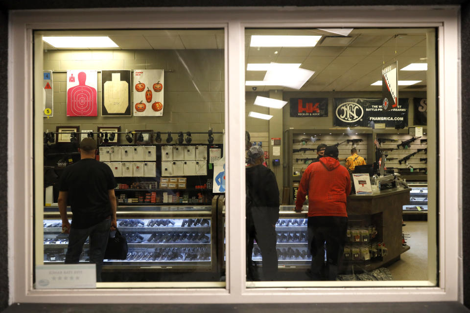 Customers stand inside the gun shop area of Maxon Shooter's Supplies and Indoor Range, as seen from the shooting range, Friday, April 30, 2021, in Des Plaines, Ill. After a year of pandemic lockdowns, mass shootings are back, but the guns never went away. As the U.S. inches toward a post-pandemic future, guns are arguably more present in the American psyche and more deeply embedded in American discourse than ever before. The past year's anxiety and loss fueled a rise in gun ownership across political and socio-economic lines. (AP Photo/Shafkat Anowar)