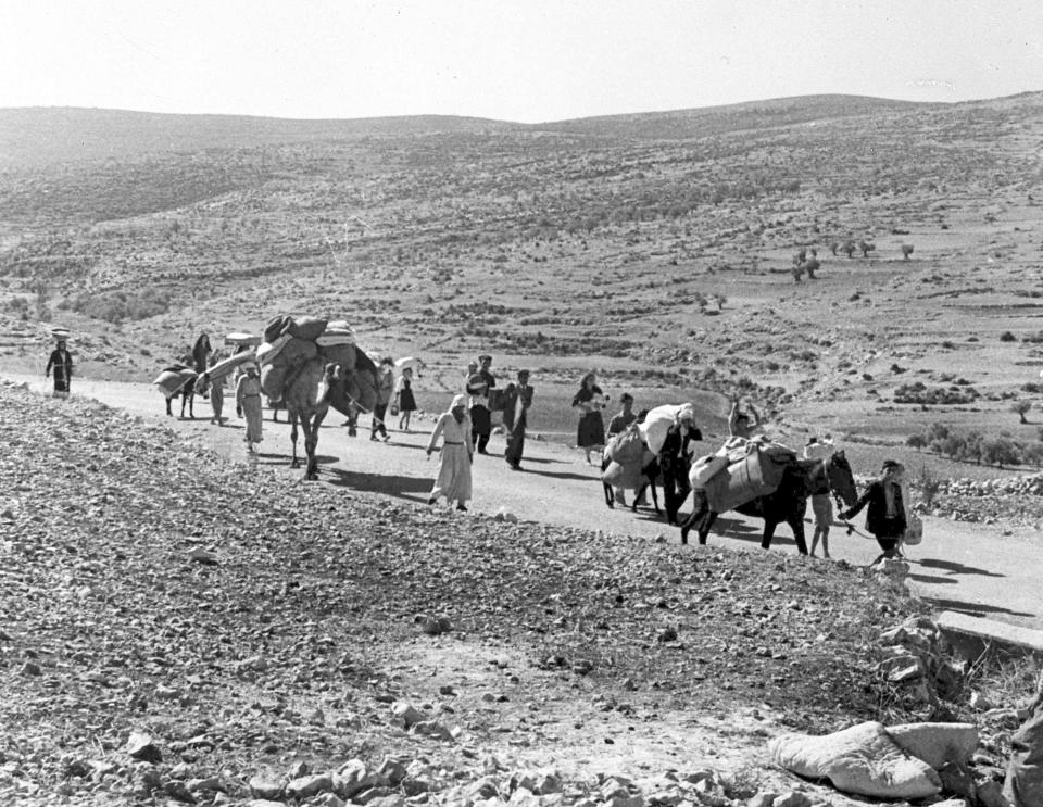 FILE - A group of Arab refugees walk along the dusty road from Jerusalem to Lebanon, carrying their children and belongings with them, on Nov. 9, 1948. (AP Photo/Jim Pringle, File)