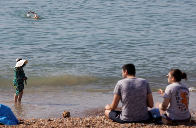 A woman wears a hat to cover from the sun during hot weather in Brighton