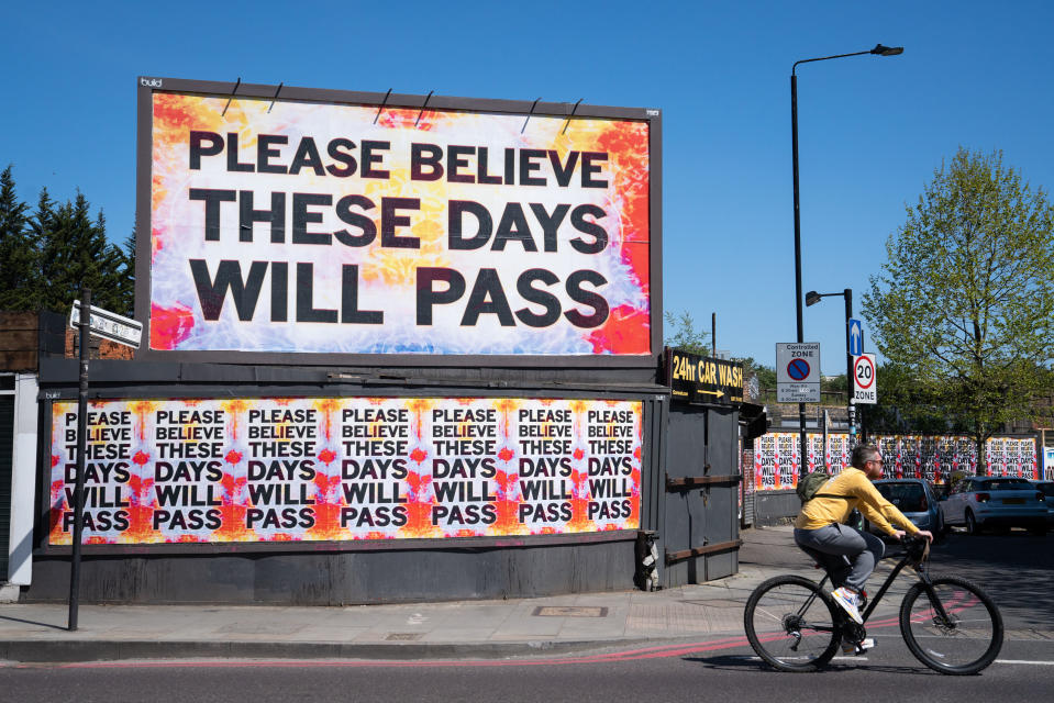 A cyclist rides past a billboard reading 'please believe these days will pass' in Shoreditch, east London, as the UK continues in lockdown to help curb the spread of the coronavirus.