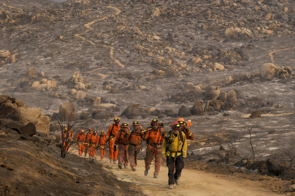 Miembros de una cuadrilla de bomberos caminan en fila antes de combatir un incendio forestal cerca de Hemet, California, el 6 de septiembre de 2022. (AP Foto/Ringo H.W. Chiu)