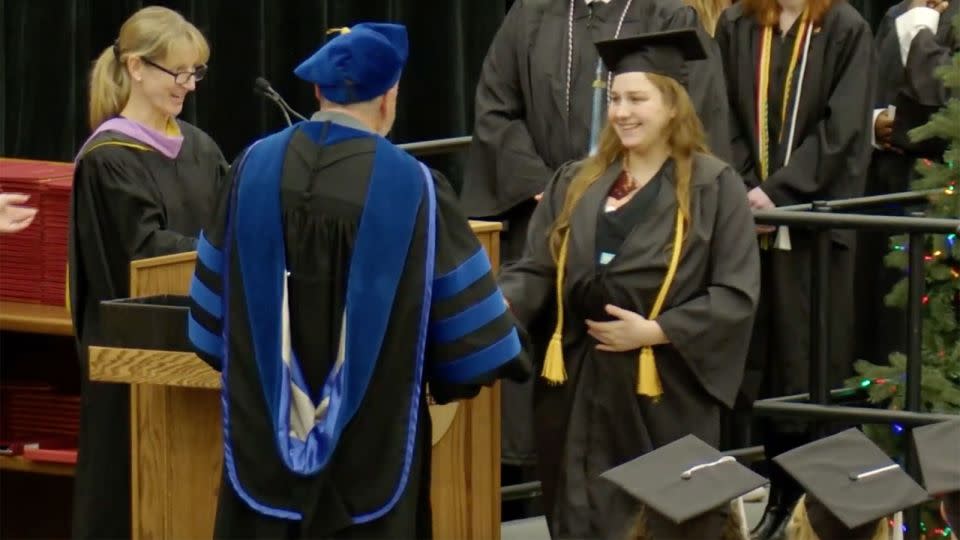 Grace Szymchack smiles as she receives her degree while holding baby Annabelle. - Ferris State University