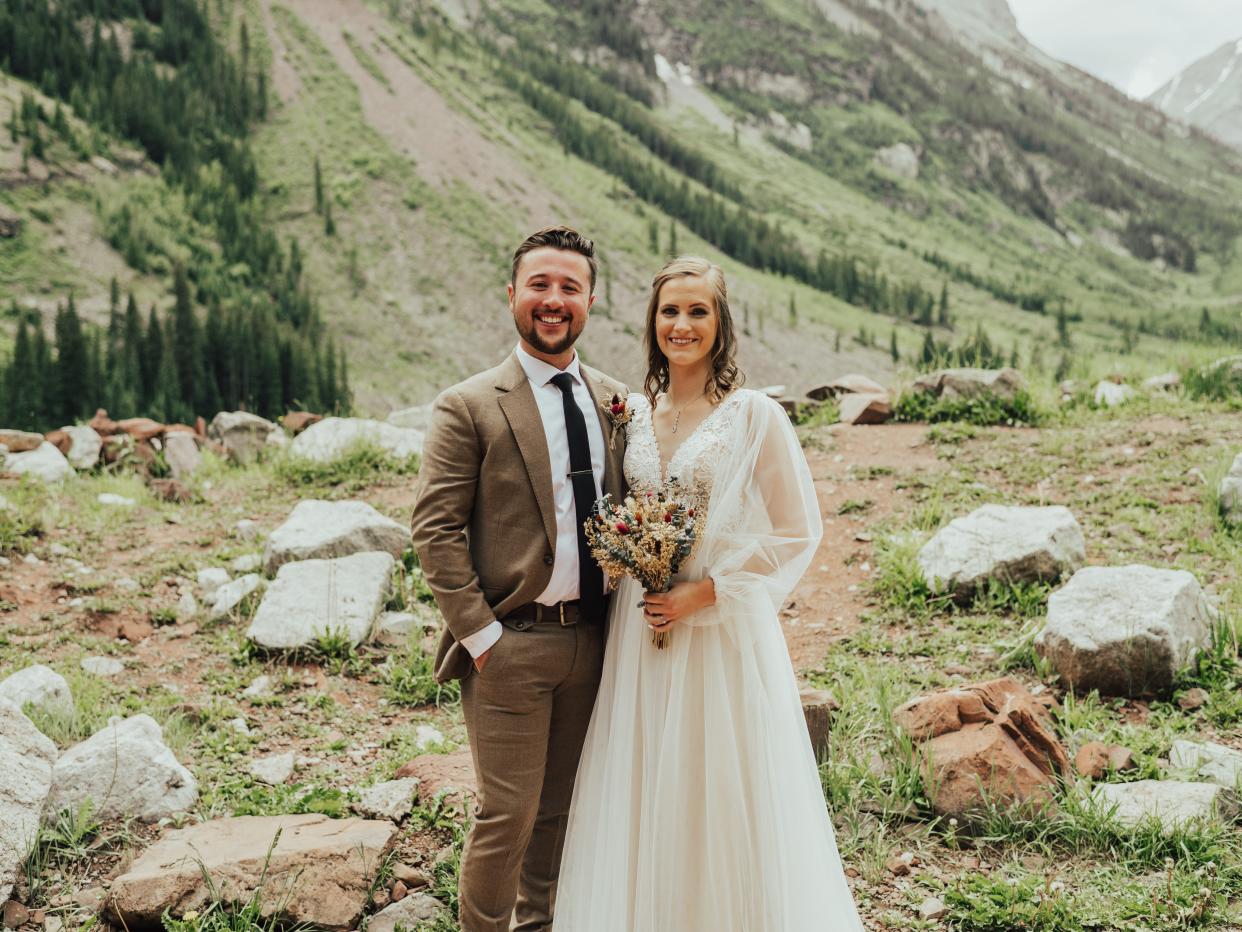 abi and her husband posing for a straight-on photo on their wedding day in maroon bells amphitheater