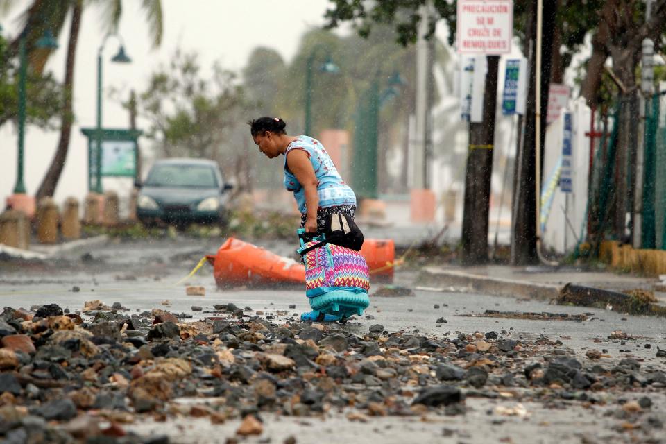 A woman pulls a suitcase along on a rock-strewn road in the aftermath of Hurricane Irma in Fajardo, Puerto Rico, on Thursday. (Photo: RICARDO ARDUENGO via Getty Images)