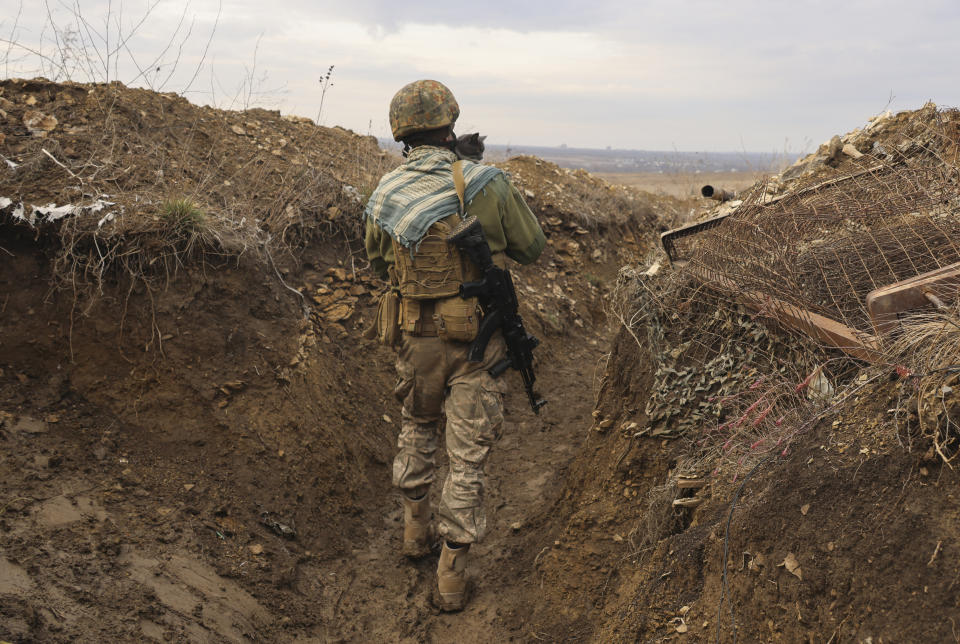 FILE - A Ukrainian soldier holds a cat and walks in a trench on the line of separation from pro-Russian rebels near Debaltsevo, Donetsk region, Ukraine, Ukraine, Dec 3, 2021. With the fate of Ukraine and potentially broader post-Cold War European stability at stake, the United States and Russia are holding critical strategic talks that could shape the future of not only their bilateral ties but the relationship between the U.S. and its NATO allies. Prospects are bleak. (AP Photo/Andriy Dubchak, file)