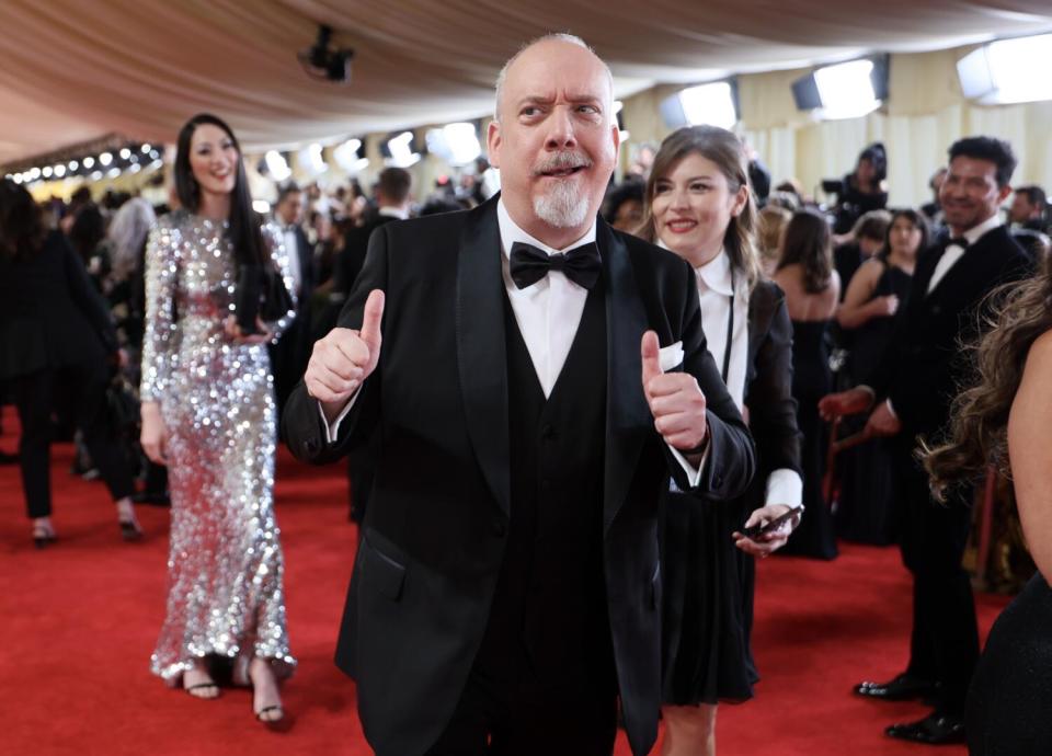 Paul Giamatti holds up two thumbs as he walk the red carpet.