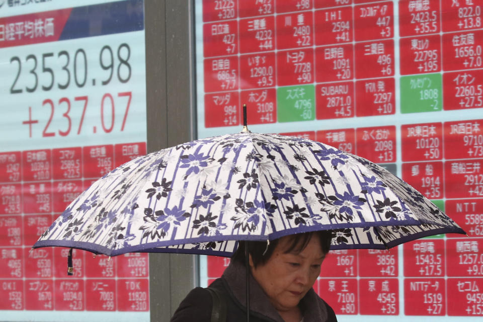 A woman walks by an electronic stock board of a securities firm in Tokyo, Monday, Dec. 2, 2019. Asian stock markets have risen after Chinese factory activity improved ahead of a possible U.S. tariff hike on Chinese imports. Benchmarks in Shanghai, Tokyo and Hong Kong advanced. (AP Photo/Koji Sasahara)