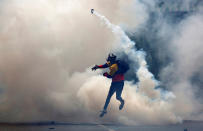 <p>An opposition supporter throws tear gas at riot police during a rally against President Nicolas Maduro in Caracas, Venezuela, May 8, 2017. (Carlos Garcia Rawlins/Reuters) </p>