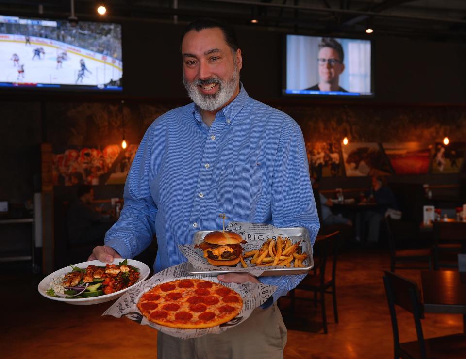 Rigsby's Smoked Burgers Wings & Grill at 176 N. Liberty Street in Spartanburg, Wednesday, December 8, 2021. The new restaurant has opened in the former Hub City Co-op building. Darryl Fenollol, field training manager at Rigsby's, holds plates of food at the restaurant.