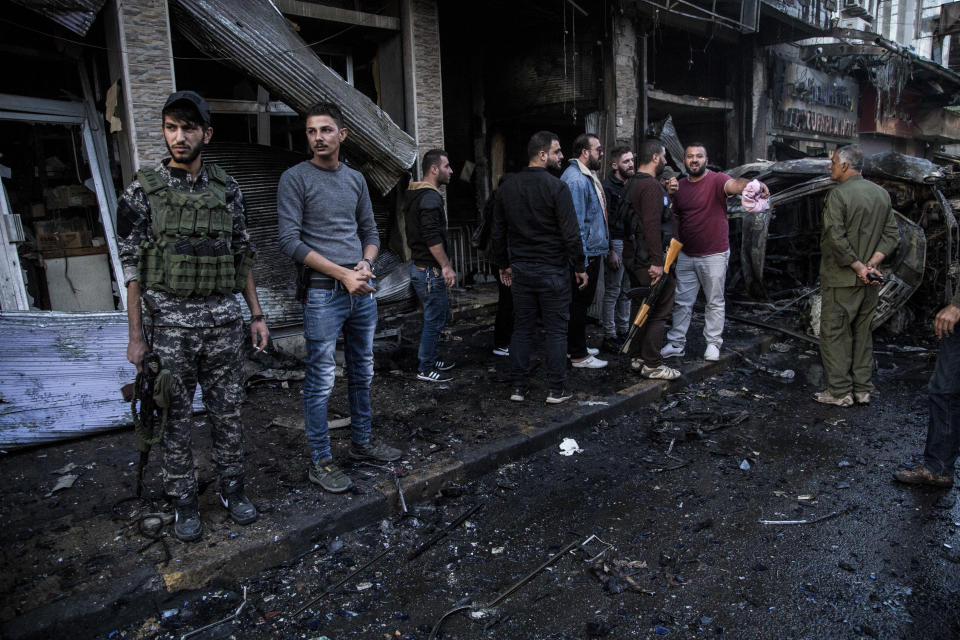 People check the aftermath of a car bomb blast in the city of Qamishli, northern Syria, Monday, Nov. 11, 2019. Three car bombs went off Monday in then city killing several and wounding tens of people. (AP Photo/Baderkhan Ahmad)
