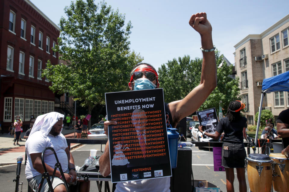 A person holds a placard and raises a fist as protesters temporarily block the street to U.S. Senate Majority Leader Mitch McConnell's (R-KY) house with a live band on a flatbed truck, demanding the extension of coronavirus disease (COVID-19)-related unemployment aid, on Capitol Hill in Washington, U.S. July 22, 2020. (Jonathan Ernst/Reuters)