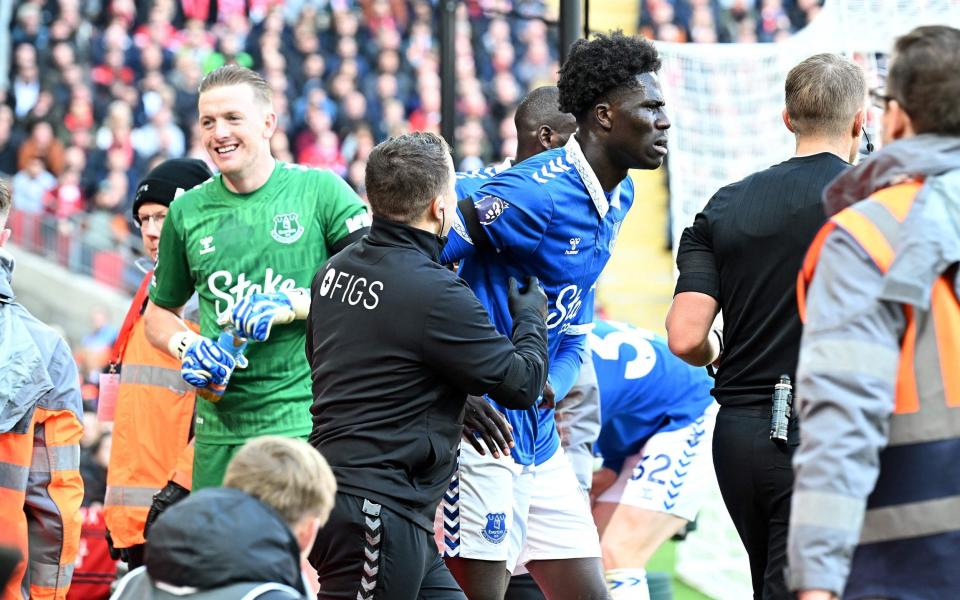 Everton's Senegalese-born Belgian midfielder #08 Amadou Onana is helped out of the advertising hosrdings