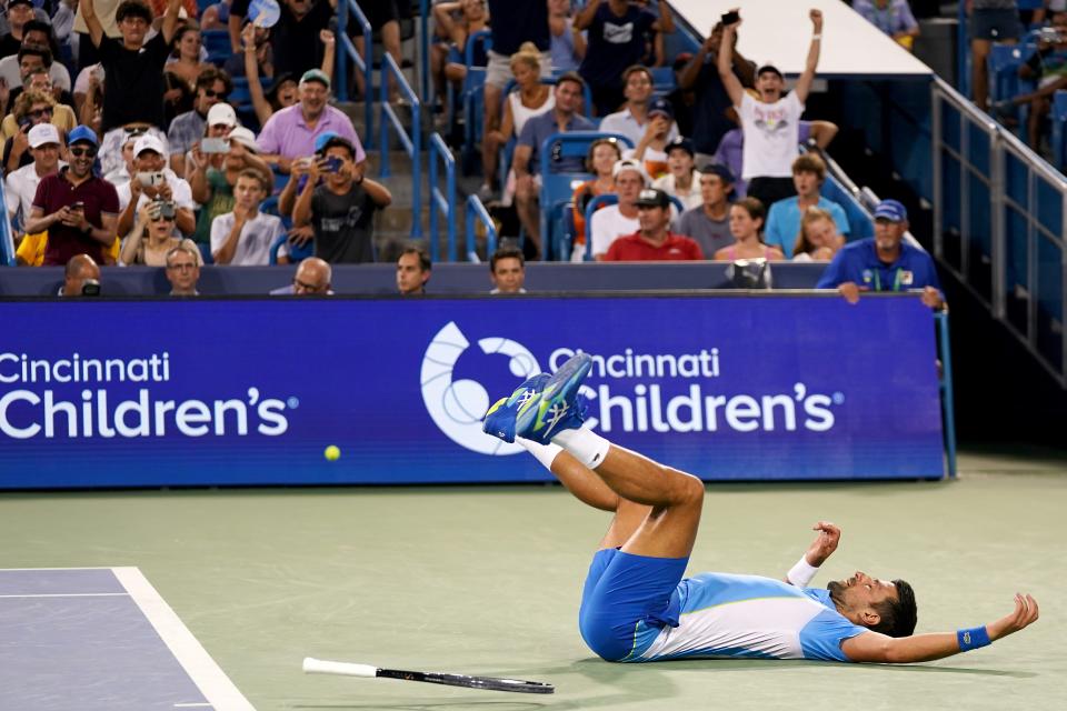Novak Djokovic, of Serbia, falls to the court in celebration after defeating Carlos Alcaraz, of Spain, at the conclusion of the men’s singles final of the Western & Southern Open tennis tournament, Sunday, Aug. 20, 2023, at the Lindner Family Tennis Center in Mason, Ohio.