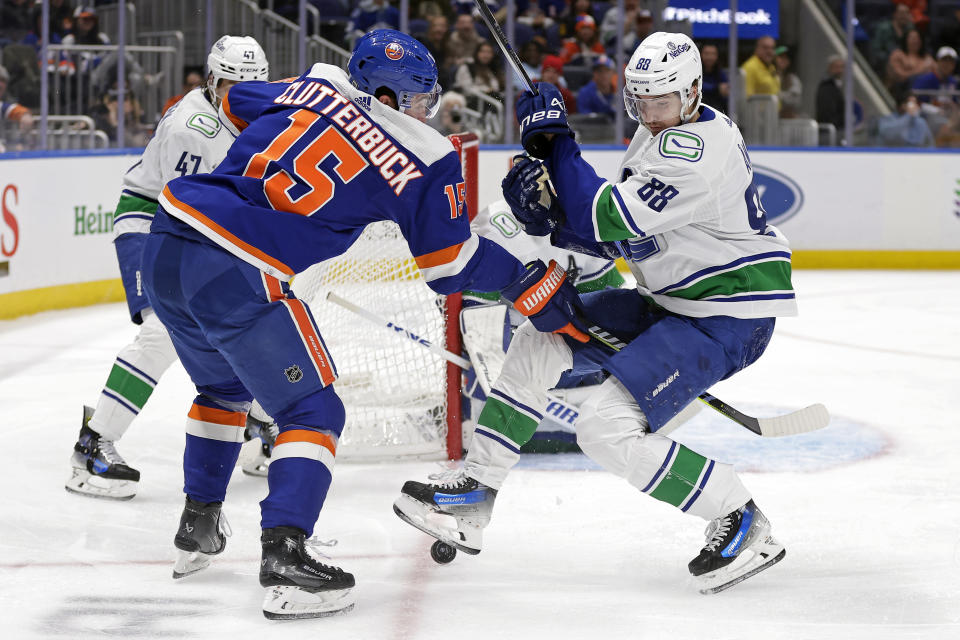 New York Islanders right wing Cal Clutterbuck (15) checks Vancouver Canucks center Nils Aman in the second period of an NHL hockey game Tuesday, Jan. 9, 2024, in Elmont, N.Y. (AP Photo/Adam Hunger)wld