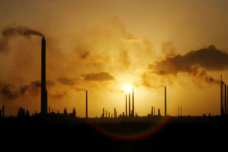 The sun sets behind Isla refinery in Willemstad on the island of Curacao June 16, 2008. REUTERS/Jorge Silva/File Photo
