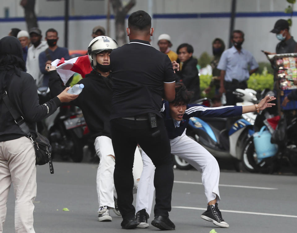 A plainclothes police officers detain protesters during a rally against the new jobs law in Jakarta, Indonesia, Tuesday, Oct. 20, 2020. Protests against Indonesia's new jobs law were held in cities across the country on Tuesday, with demonstrators calling on the president to revoke the legislation they say will erode labor rights and weaken environmental protections. (AP Photo/Achmad Ibrahim)