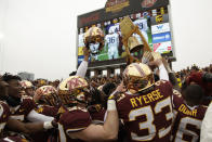 FILE - In this Nov. 9, 2019, file photo, Minnesota football players hold up the Governor's Victory Bell after winning 31-26 against Penn State during an NCAA college football game in Minneapolis. Big Ten is going to give fall football a shot after all. Less than five weeks after pushing football and other fall sports to spring in the name of player safety during the pandemic, the conference changed course Wednesday, Sept. 16, 2020, and said it plans to begin its season the weekend of Oct. 23-24. (AP Photo/Stacy Bengs, File)