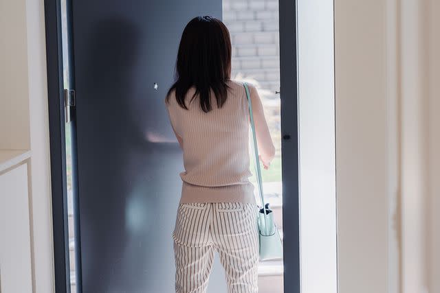 <p>maroke/Getty</p> Woman opening door