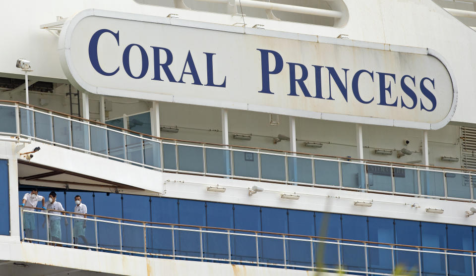 CORRECTS THE MONTH - Coral Princess cruise crew members looks from their balcony at PortMiami as the coronavirus pandemic continues on Sunday, April 5, 2020 in Miami. (David Santiago/Miami Herald via AP)