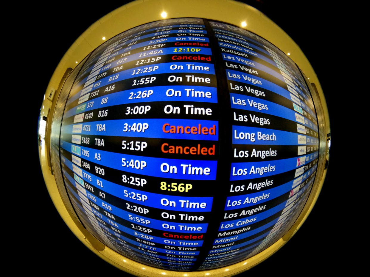 This image made with a fish-eye lens shows a departure board at Salt Lake City International Airport Wednesday, Jan. 5, 2022, in Salt Lake City. (AP Photo/Rick Bowmer)