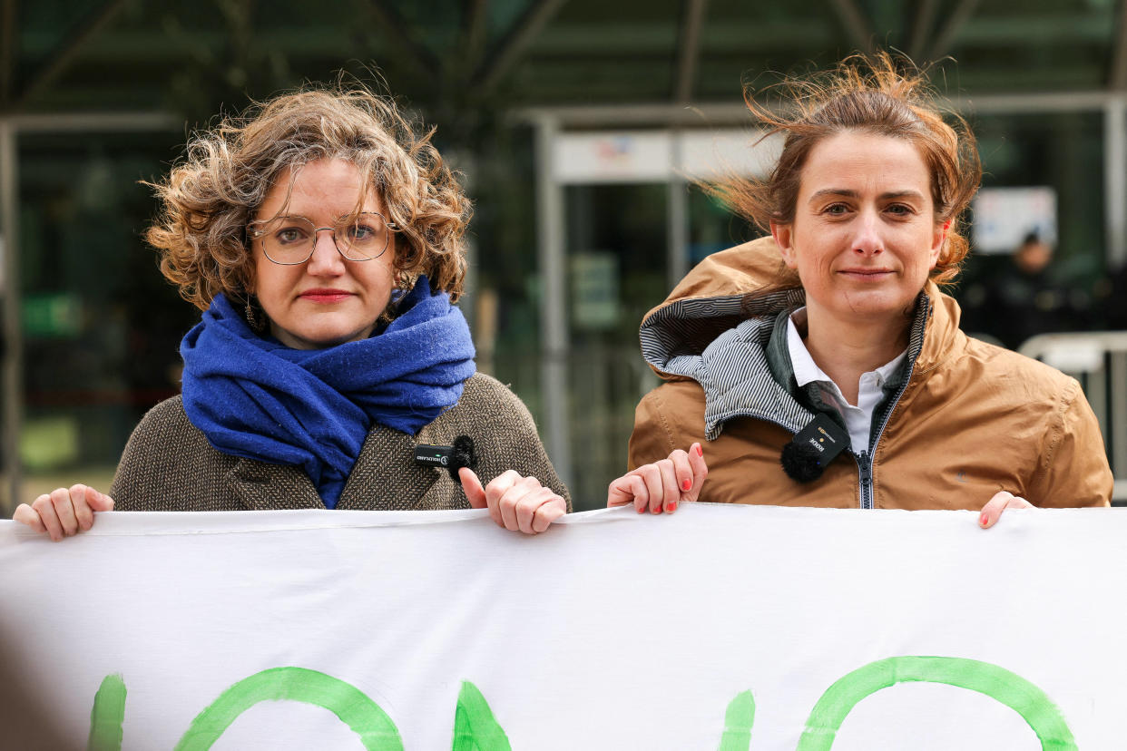 Marie Toussaint et Marine Tondelier tiennent une banderole devant la tour de TotalÉnergies à La Défense, à Paris, ce 28 mars.