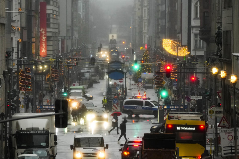 People cross the shopping street Friedrichstrasse in central Berlin, Germany, Tuesday, Nov. 30, 2021. According to local authorities, except of shops for essential needs, only people which are vaccinated or recovered from coronavirus are allowed to enter shops. (AP Photo/Markus Schreiber)