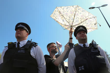 A climate change activist holds an umbrella for police officers during the Extinction Rebellion protest on Waterloo Bridge in London, Britain April 20, 2019. REUTERS/Simon Dawson