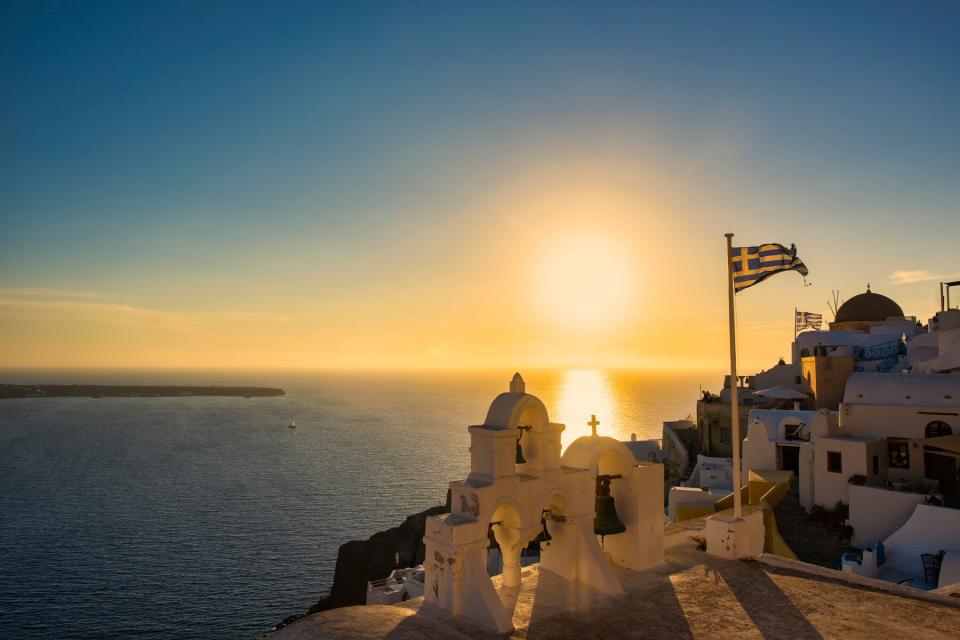 Sunset behind the blue domes of Oia village, Santorini, Greece