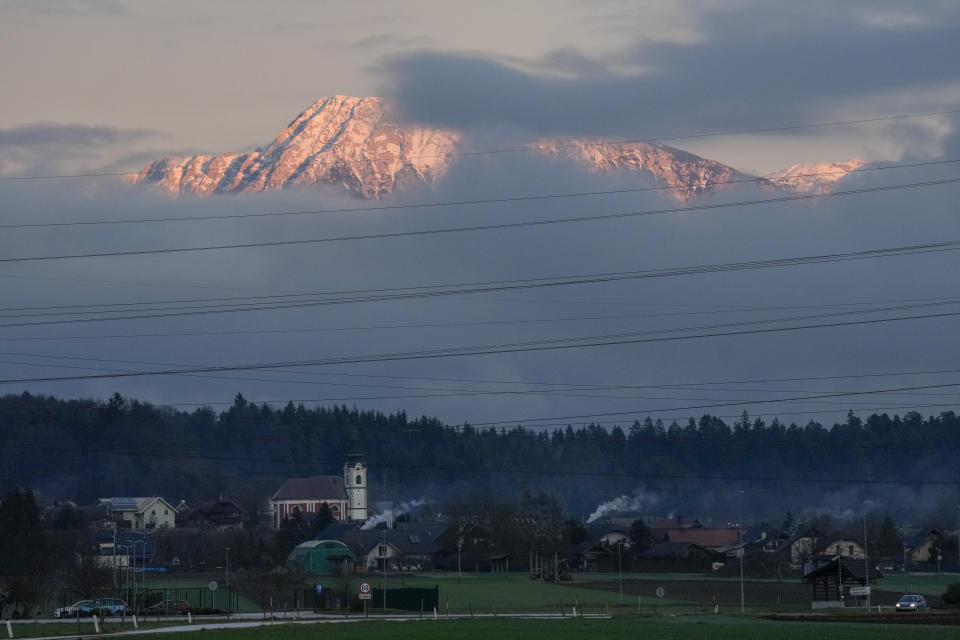 FILE - Alpine peaks which would normally be covered by snow are seen above the village of Naklo, Slovenia, Wednesday, Jan. 4, 2023. Sparse snowfall and unseasonably warm weather in much of Europe is allowing green grass to blanket many mountaintops across the region where snow might normally be. It has caused headaches for ski slope operators and aficionados of Alpine white this time of year. (AP Photo/Darko Bandic, File)