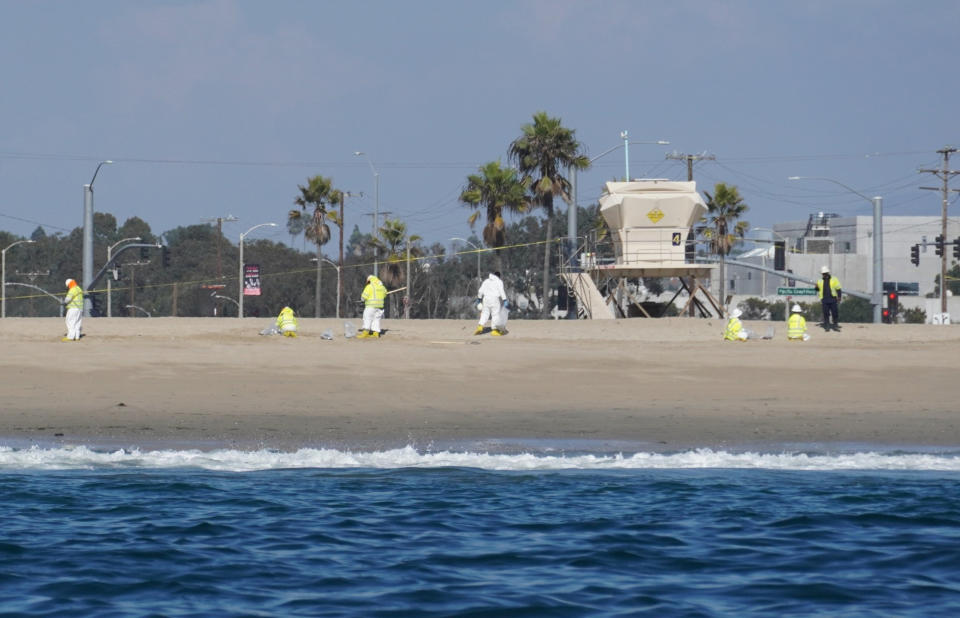 Cleanup crews walking along the beach inspect beach areas and retrieve oil spill debris deposited in Huntington Beach, Calif., Tuesday, Oct. 5, 2021. An oil spill sent up to 126,000 gallons of heavy crude into the ocean. It contaminated the sands of famed Huntington Beach and other coastal communities. (AP Photo/Eugene Garcia)