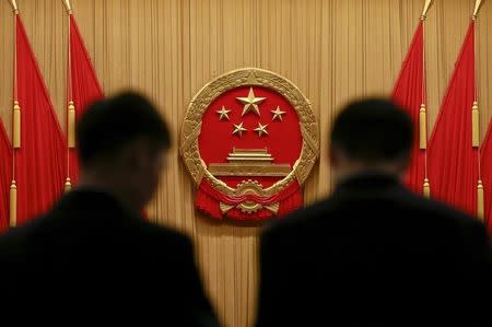 Security officers stand near the Chinese national emblem as they carry out a check after delegates left at the end of the opening session of the National People's Congress (NPC) at the Great Hall of the People in Beijing, China, March 5, 2016. REUTERS/Kim Kyung-hoon