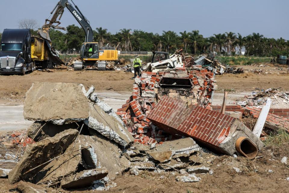 A fallen brick chimney sits amid rubble from a demolished home.