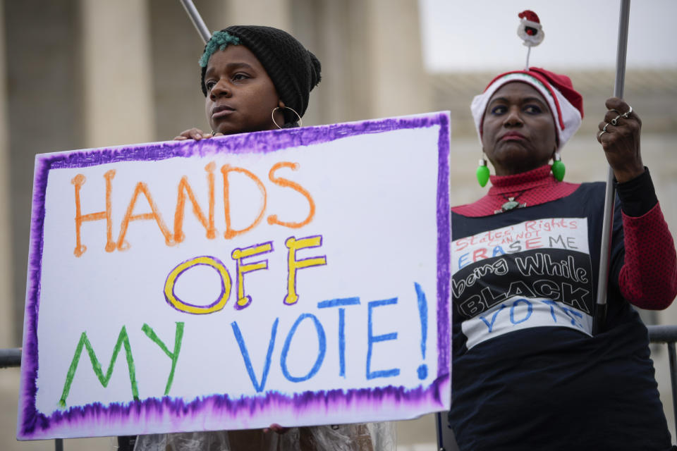 Voting rights activists rally holding a sign that says: Hands Off My Vote!