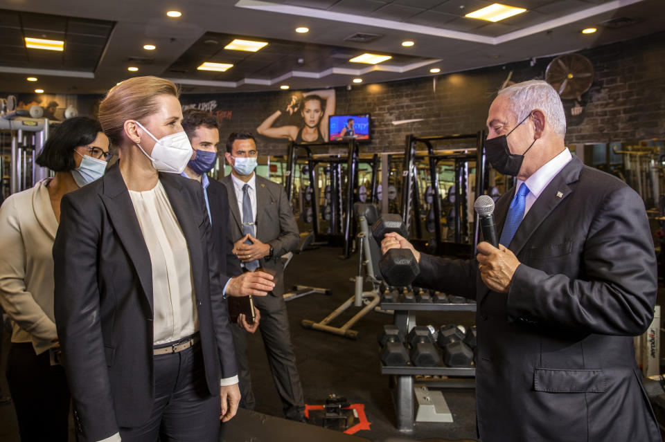 Israeli Prime Minister Benjamin Netanyahu, holds a barbell as he speaks to Danish Prime Minister Mette Frederiksen, left, during a visit a fitness gym with Austrian Chancellor Sebastian Kurz, to observe how the "Green Pass," for citizens vaccinated against COVID-19, is used, in Modi'in, Israel, Thursday, March 4, 2021. Frederiksen and Kurz are on a short visit to Israel for to pursue the possibilities for closer cooperation on COVID-19 and vaccines. (Avigail Uzi/Pool via AP)