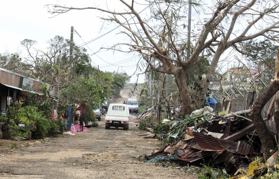 Local residents stand outside their homes on a road littered with debris after Cyclone Pam hit Port Vila, the capital city of the Pacific island nation of Vanuatu