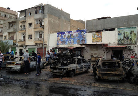 People look at the remnants of a car at the scene of a car bomb in Benghazi, Libya, November 21, 2016. REUTERS/Stringer